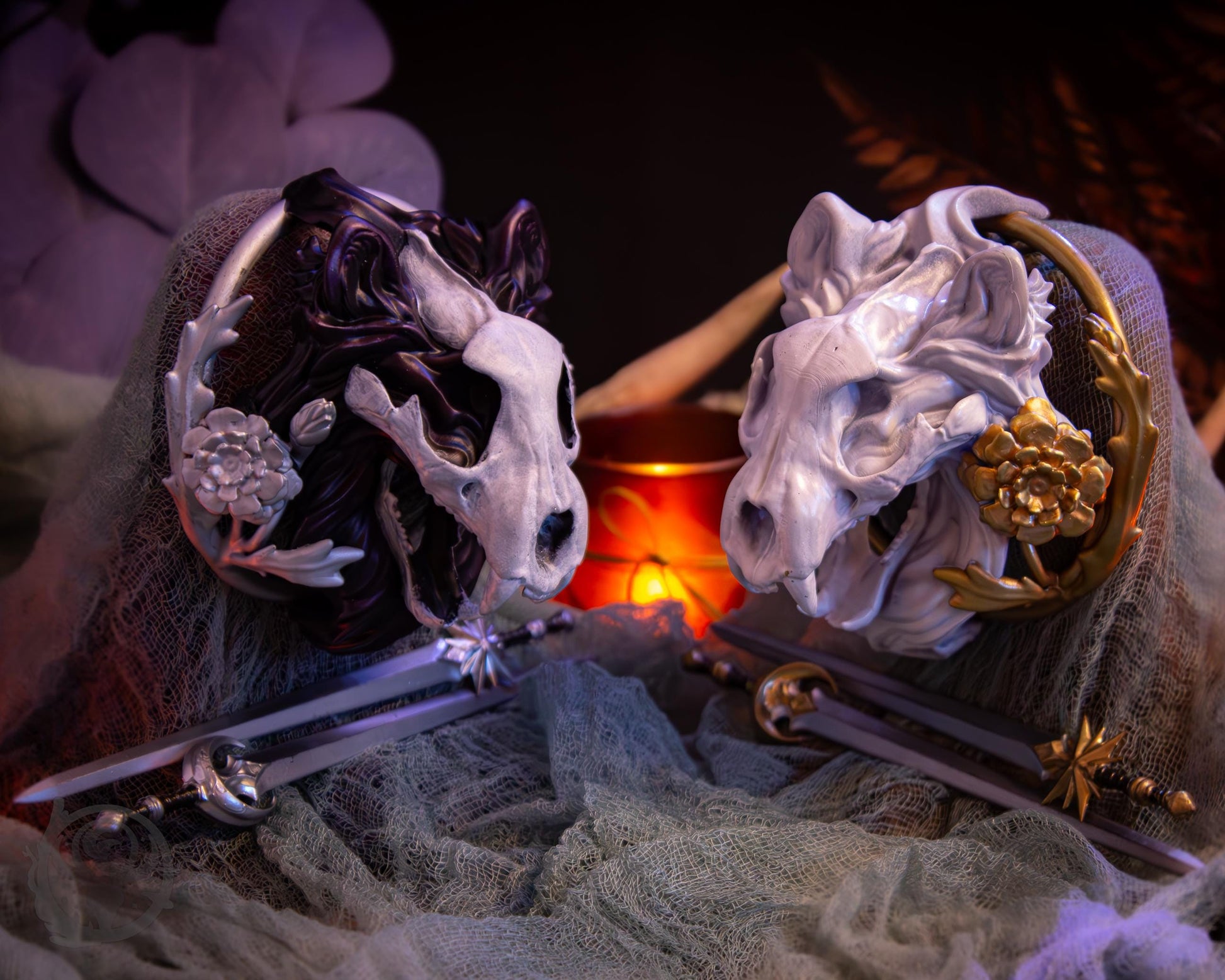 Two resin hair bun covers set up on stands, with their resin sword pins. The bun covers are lion skulls with gilded marigold.
