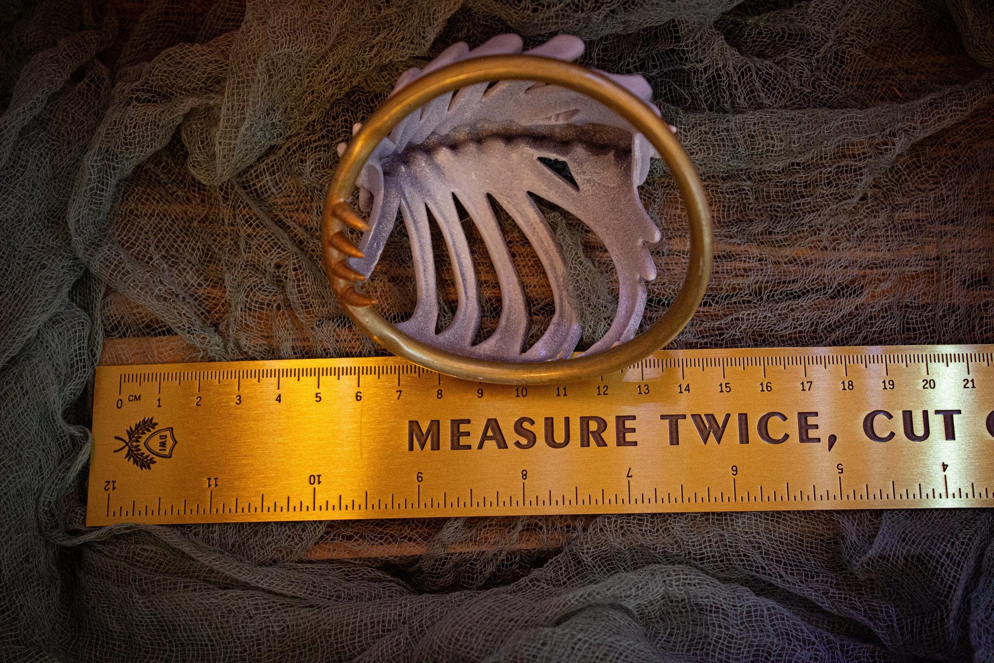 Measurement of the bun cover showing the underside and hooks (~10cm in length)