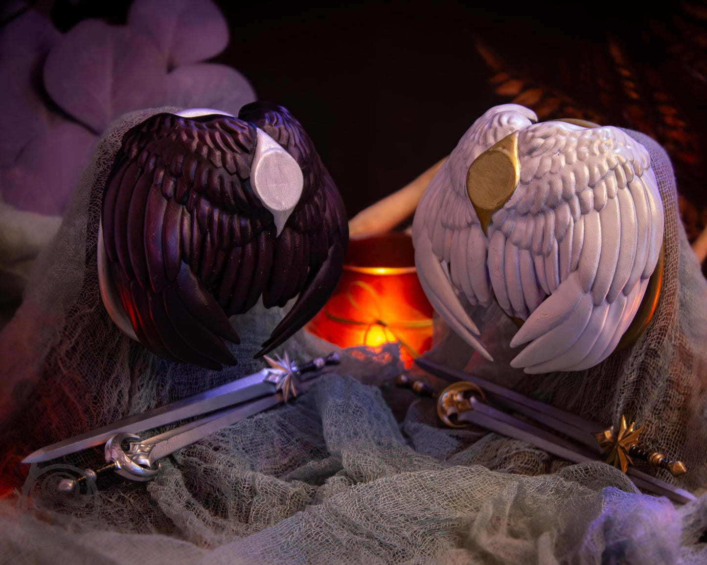 Two resin hair bun covers set up on stands, with their resin sword pins. The bun covers are feathered wings.