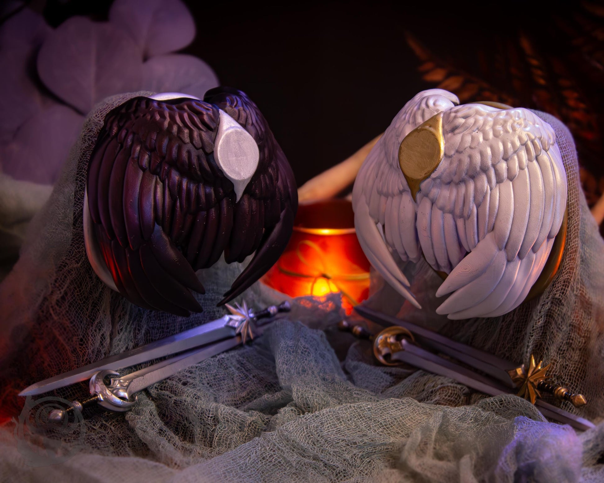 Two resin hair bun covers set up on stands, with their resin sword pins. The bun covers are feathered wings.